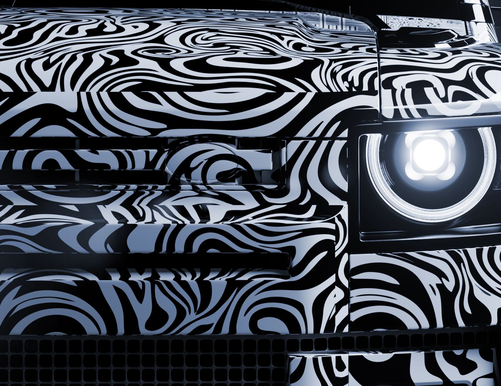 Front of a build in black-and-white camouflage wrap, its round headlamp lit